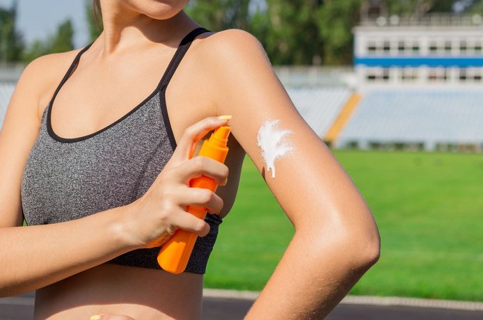 ©sosiukin - stock.adobe.com Frau cremt sich vor dem Sport mit Sonnencreme ein.
