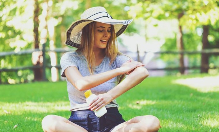 ©Tierney - stock.adobe.com Frau cremt sich mit Sonnencreme ein.