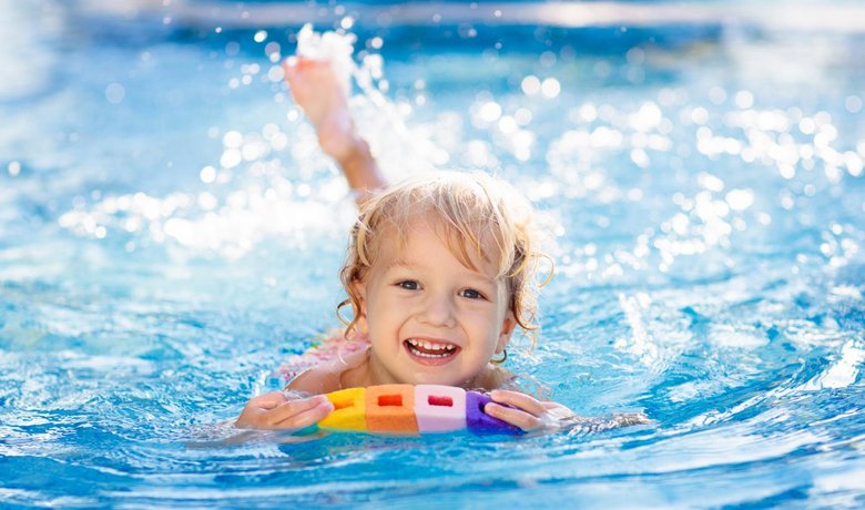 Kind schwimmt mit Schwimmreifen im Pool