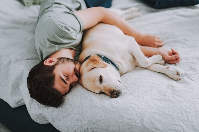 Mann kuschelt mit seinem Hund.
